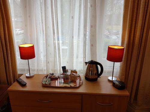una mesa con dos lámparas en un tocador con ventana en Green Gables Guest House, en Windermere