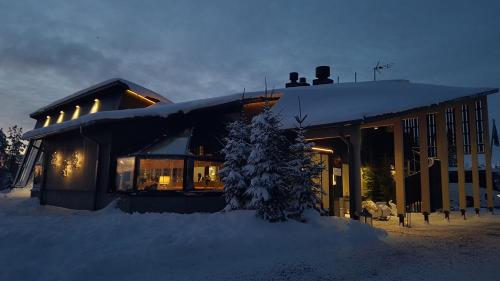 a building covered in snow with a tree in front of it at Santa's Igloos Arctic Circle in Rovaniemi