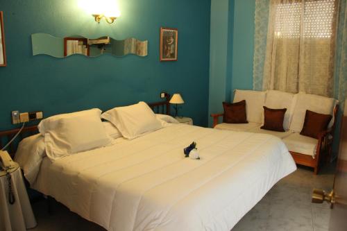 a bedroom with a large white bed with a cat sitting on it at Hotel Vazquez Diaz in Nerva