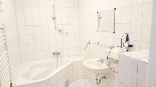 La salle de bains blanche est pourvue d'une baignoire et d'un lavabo. dans l'établissement Pension San Francisco, à Vienne