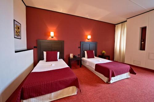 two beds in a room with red walls at Hotel Aurelia in Timişoara