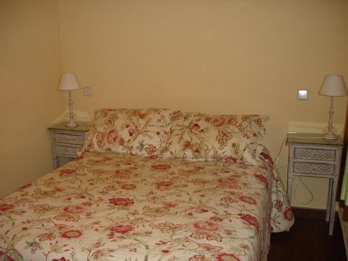 a bedroom with a bed with a floral bedspread and two night stands at Hostal Puerta Bonita Vista Alegre in Madrid