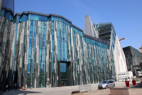 a large glass building with cars parked in front of it at Ferienhaus Kaiserhof in Markkleeberg