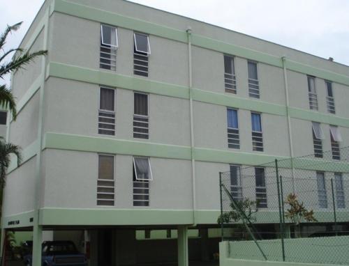 a large white building with windows and a fence at Apartamento Peruíbe in Peruíbe