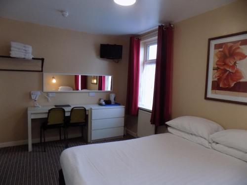 a hotel room with a bed and a desk and a window at The Beechfield Hotel in Blackpool