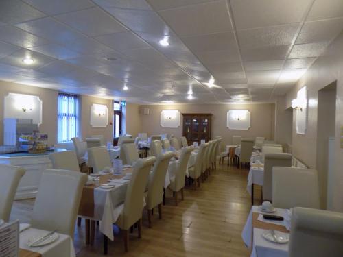 a dining room with white tables and white chairs at The Beechfield Hotel in Blackpool