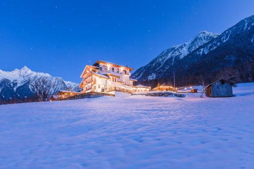 a house in the snow at night with mountains at Aktiv Panoramahotel Daniel in Sautens