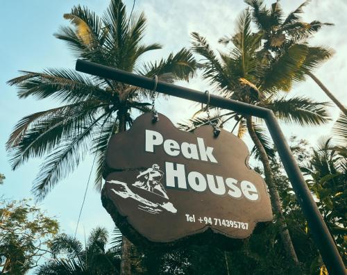 a sign for a peak house in front of palm trees at Peak House in Hiriketiya