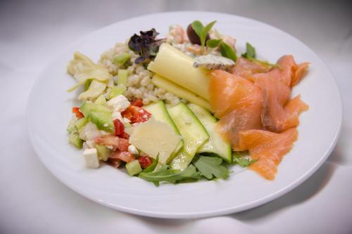 a white plate with a salad with salmon and vegetables at Hotel Krona Domžale in Domžale