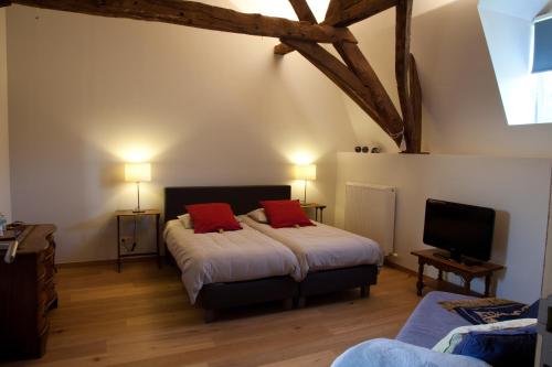 een slaapkamer met 2 bedden en rode kussens bij B&B Het Agnetenklooster in Maaseik