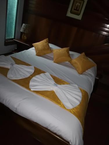 a bed with white sheets and yellow pillows at Hotel Don Robert in Puntarenas