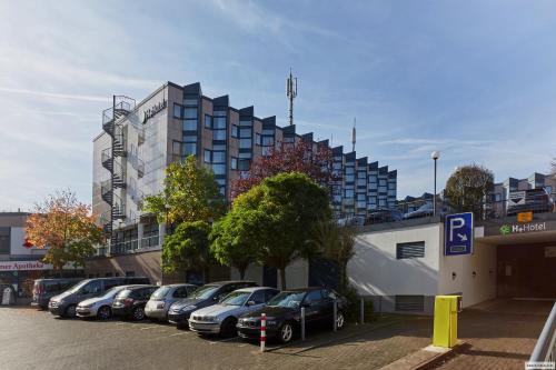 a parking lot with cars parked in front of a building at H+ Hotel Köln Brühl in Brühl