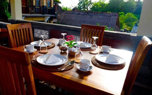 a wooden table with plates and cups and flowers on it at Wiki Bali in Ubud