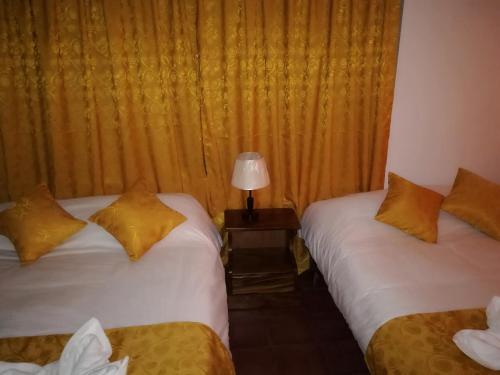 a room with two beds and a lamp on a table at Hotel Don Robert in Puntarenas