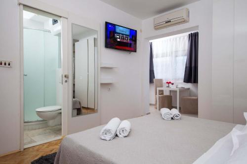 a bedroom with a bed and a toilet and a television at Villa Makarana Apartments in Makarska