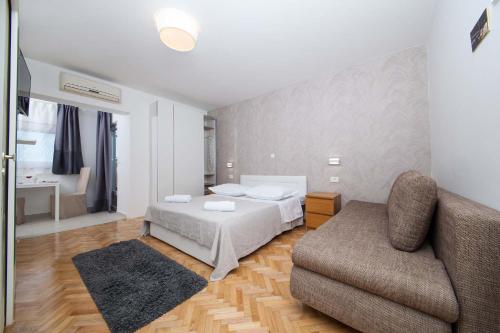 a bedroom with a bed and a couch and a chair at Villa Makarana Apartments in Makarska