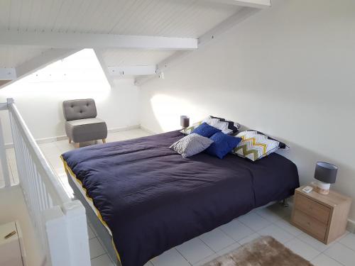 a bedroom with a large blue bed with a chair at Joli T2 à 5 min de la plage in Le Gosier