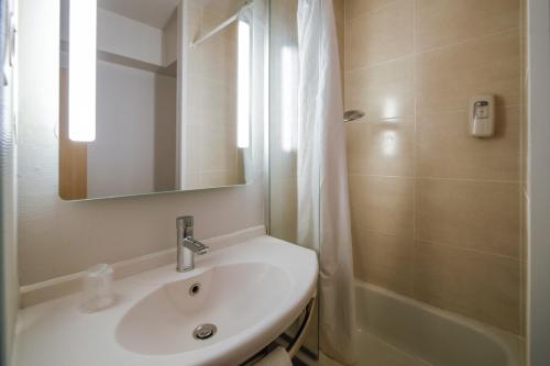 a bathroom with a sink and a shower and a mirror at B&B HOTEL Nantes Atlantis Le Zenith in Saint-Herblain