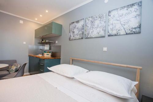 a bedroom with a bed with three paintings on the wall at Villa Makarana Apartments in Makarska