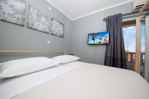 a bedroom with a white bed and a tv on the wall at Villa Makarana Apartments in Makarska