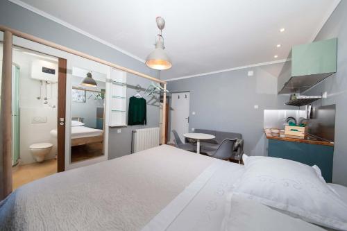 a bedroom with a large white bed and a bathroom at Villa Makarana Apartments in Makarska