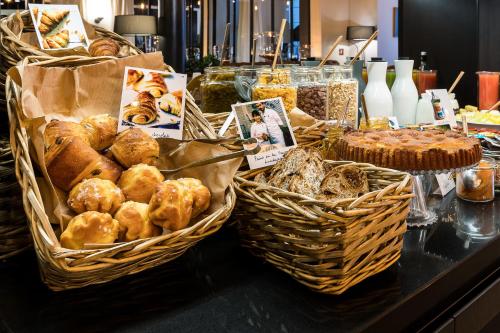 a table topped with baskets of bread and pastries at Laz' Hotel Spa Urbain Paris in Paris