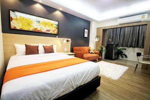 um quarto de hotel com uma cama grande e uma cadeira em Modern Studio in Nimman - Walking Distance to Mall em Chiang Mai