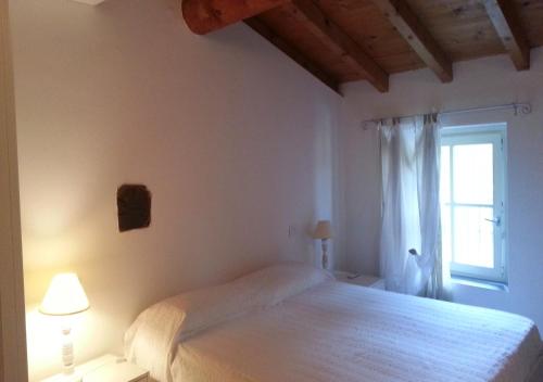 a white bedroom with a bed and a window at La Davana Parma in Salsomaggiore Terme