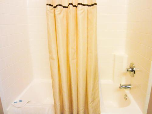 a bathroom with a shower curtain next to a tub at Bell's Extended Stay and Suites in Saint Robert