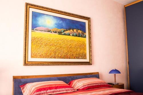 a painting of a field on a wall above a bed at Amarcord casa vacanze in Alberobello
