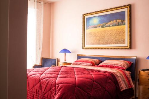 a bedroom with a red bed with a painting on the wall at Amarcord casa vacanze in Alberobello