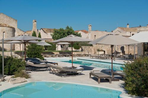 a swimming pool with lounge chairs and umbrellas at Hist&ograve; San Pietro Sul Mar Piccolo in Taranto