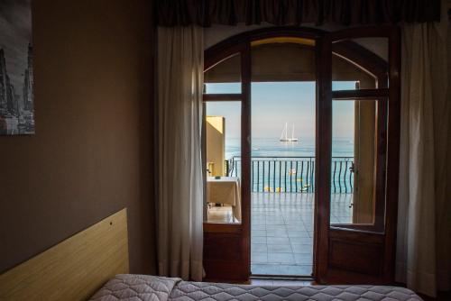 a bedroom with a sliding glass door with a view of the ocean at Hotel La Sirenetta in Giardini Naxos