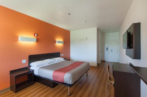 a bedroom with a bed with an orange wall at Motel 6-Bedford, TX - Fort Worth in Bedford