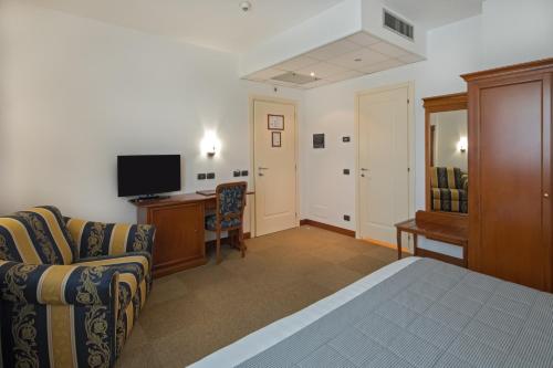 een slaapkamer met een bed, een bureau en een televisie bij Hotel Medea - Adults Only in Alba