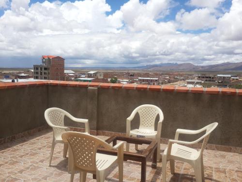 een patio met 3 stoelen en een tafel op een dak bij Hotel Aguilar in Uyuni