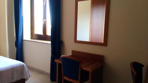 a bedroom with a desk and a mirror and a bed at Hotel La Falconara in Castrovillari