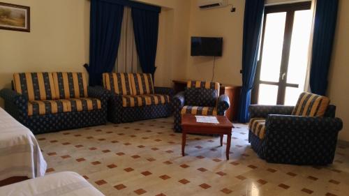pokój hotelowy z krzesłami, kanapą i telewizorem w obiekcie Hotel La Falconara w mieście Castrovillari