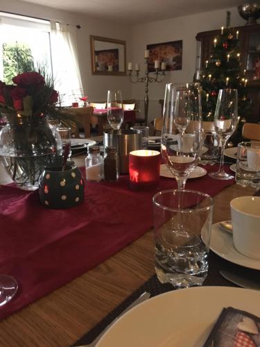 a dining table with wine glasses and a christmas tree at Gästehaus Zur Linde in Otterndorf