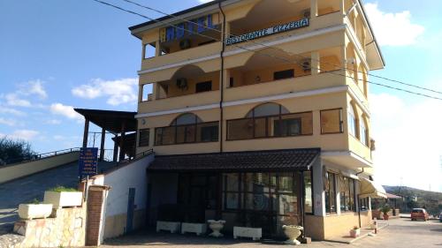 a tall yellow building with a store front at Hotel La Falconara in Castrovillari