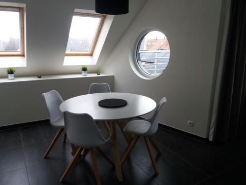 een witte tafel en stoelen in een kamer met een raam bij Vakantie Appartement Ella in De Haan