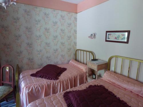 two beds in a room with pink sheets and wallpaper at Beau Site Guimauve et Vieilles Dentelles in Royères-Saint-Léonard