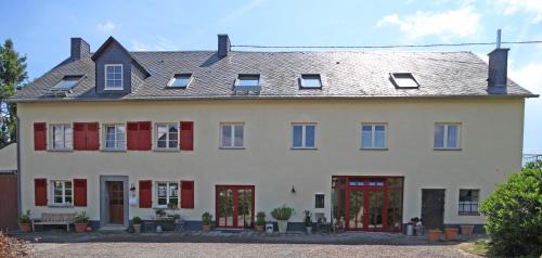 a large white house with red shutters at Landhof Lieg - Ferienwohnungen in Lieg