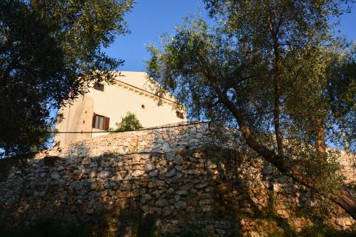 a building behind a stone wall with trees at Torre Bruno in Carpino