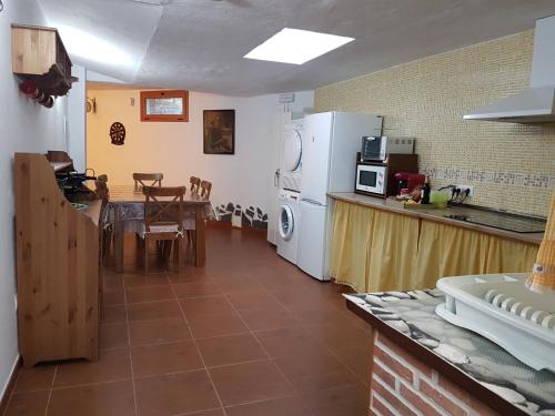 a kitchen with a table and a white refrigerator at Casa Rural La Hoyita de Tunte in San Bartolomé