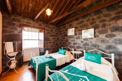 um quarto com 2 camas num quarto com uma parede de pedra em Adega Lopes em Santo Amaro
