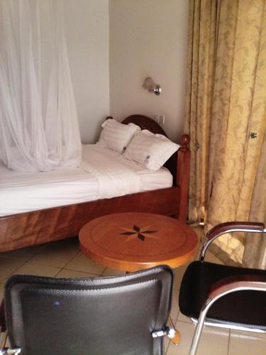 um pequeno quarto com uma cama com uma mesa e uma cadeira em Western Meridian Hotel Ltd Bushenyi em Bushenyi