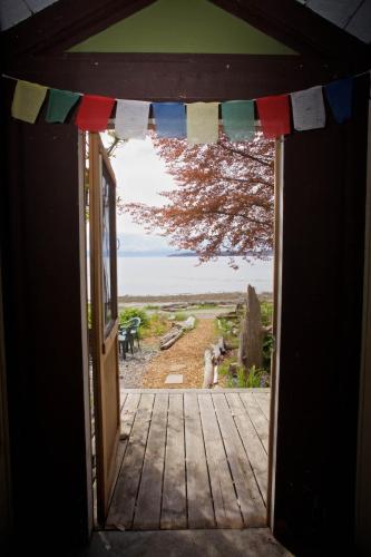 an open door to a porch with a view of a yard at Halfmoon Haven Beach Cottage or Oceanview Suite in Halfmoon Bay