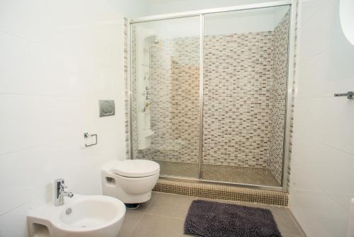 een badkamer met een douche, een toilet en een wastafel bij Pegada By Algartur in Tavira