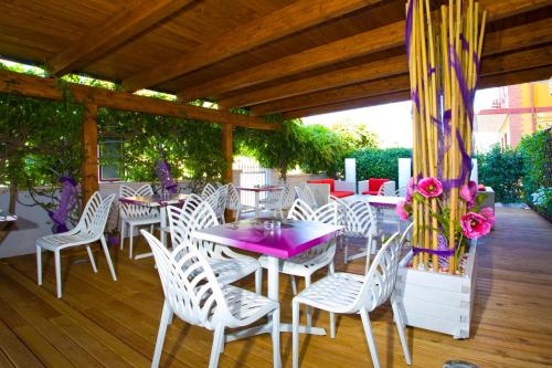 un patio con sillas y mesas blancas y una mesa púrpura. en Albergo Ristorante Protti, en Cattolica